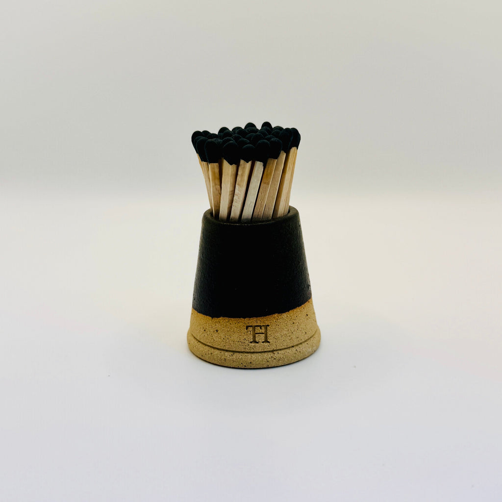 Matches in a black and cork holder on a white background