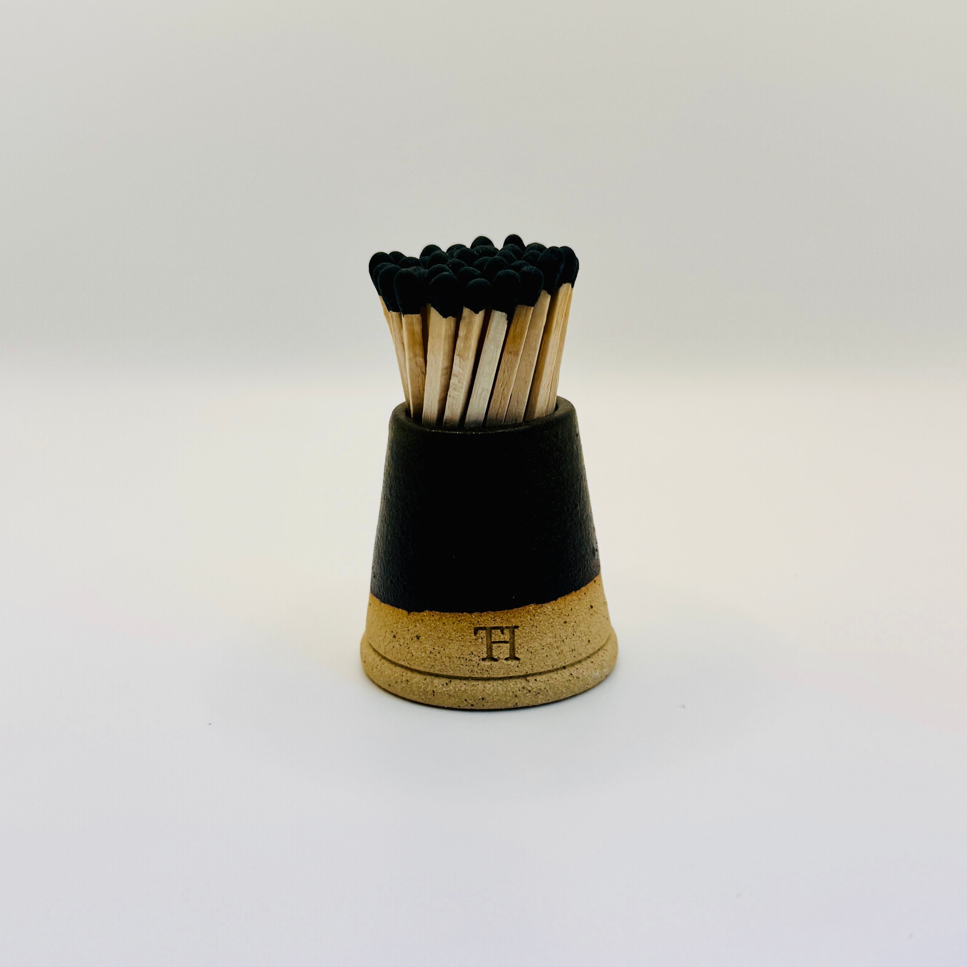 Matches in a black and cork holder on a white background