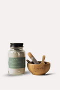 Jar of 'Green Seaweed Queen' with wooden mortar and pestle on a white background