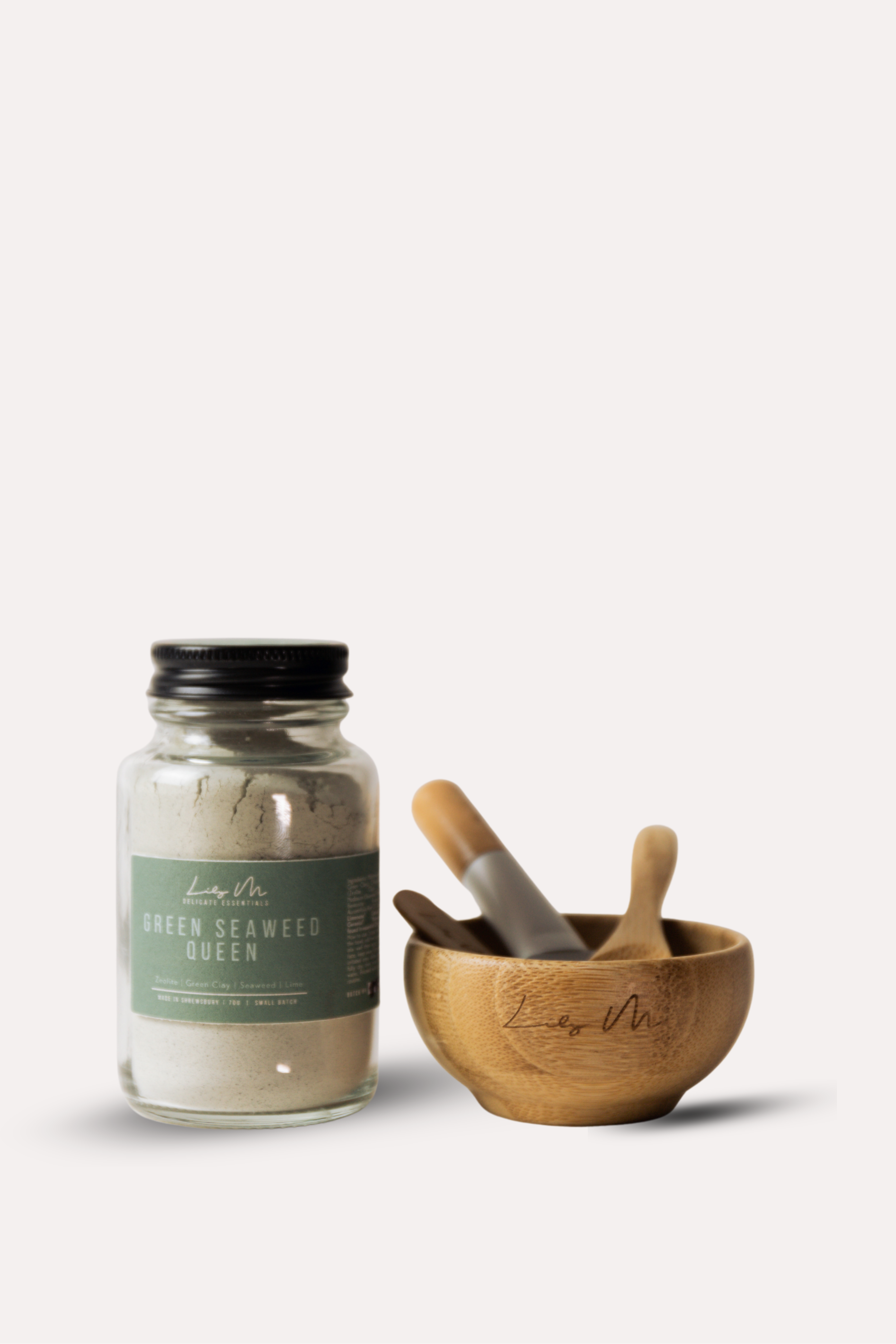 Jar of 'Green Seaweed Queen' with wooden mortar and pestle on a white background
