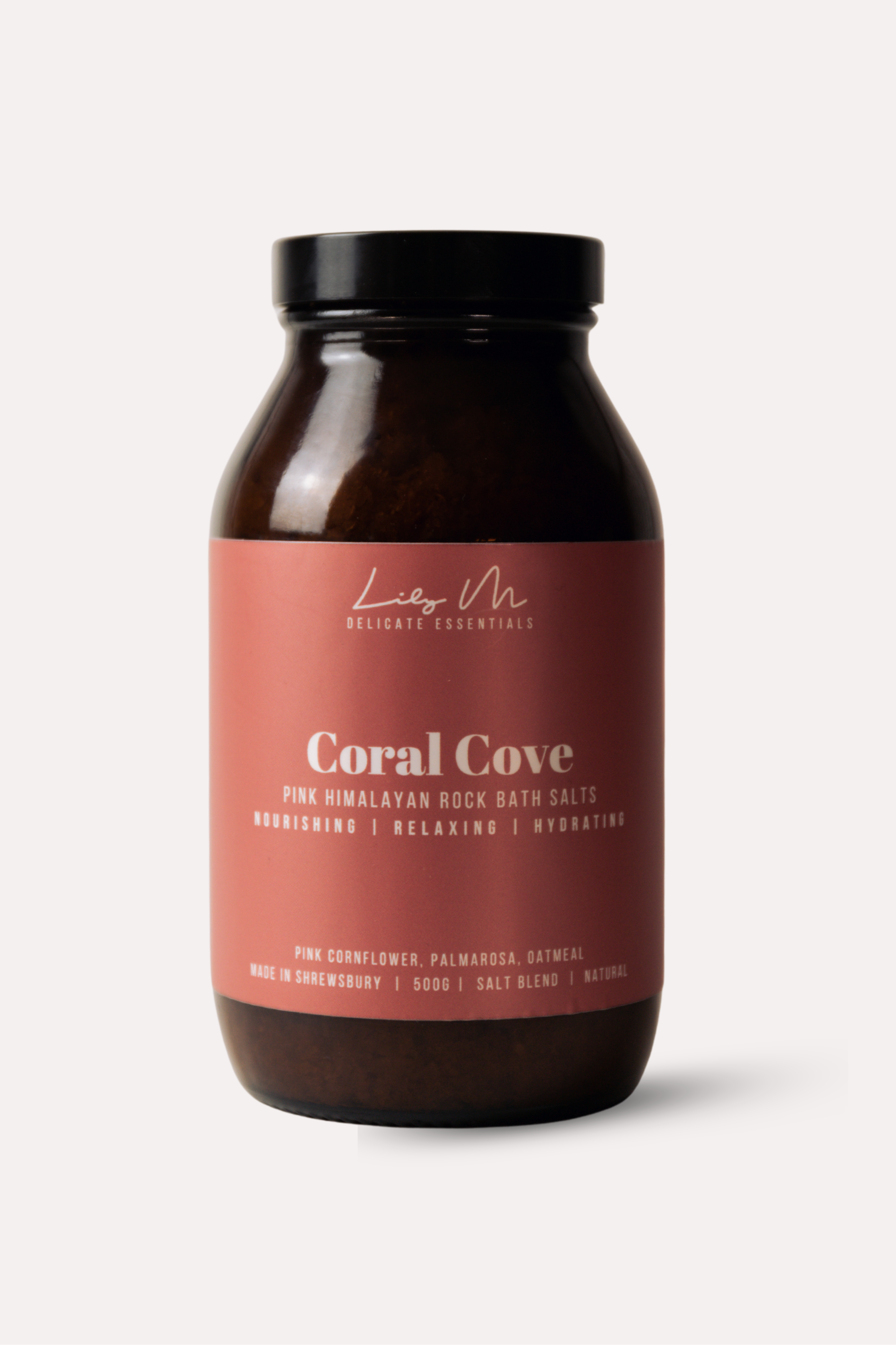 Bottle of Coral Cove bath salts with a pink label on a white background