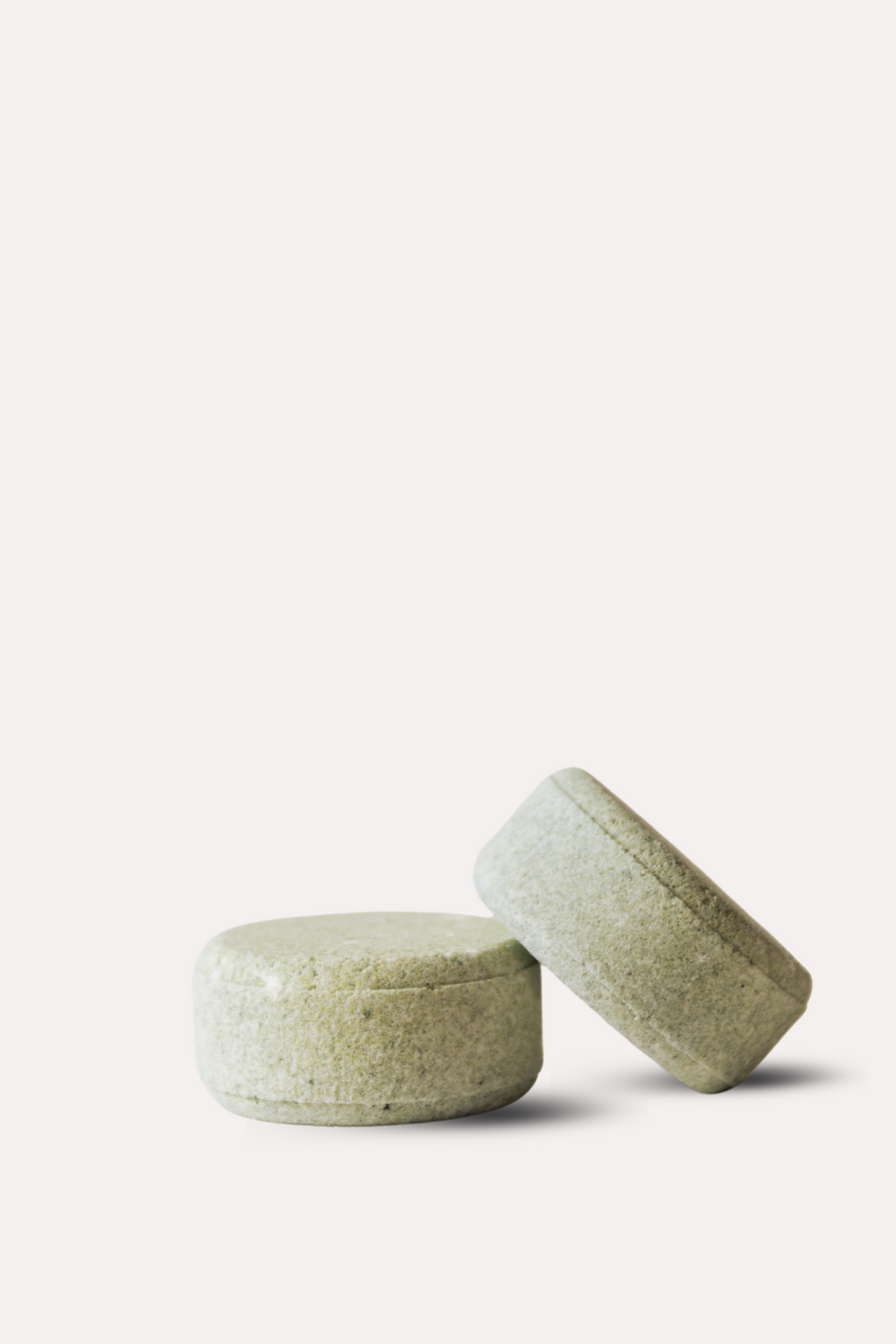 Two green bath bombs on a white background
