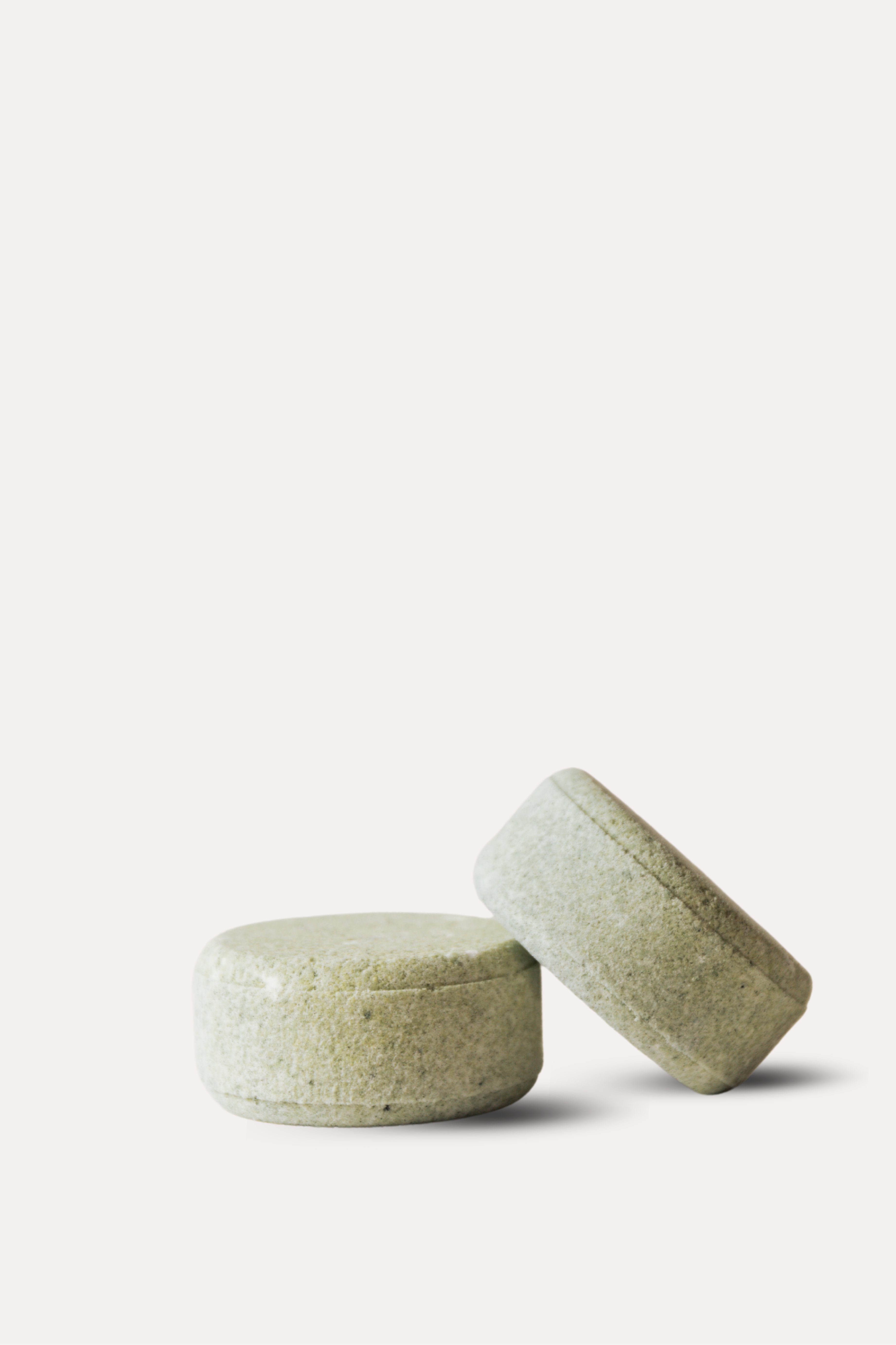 Two green bath bombs on a white background