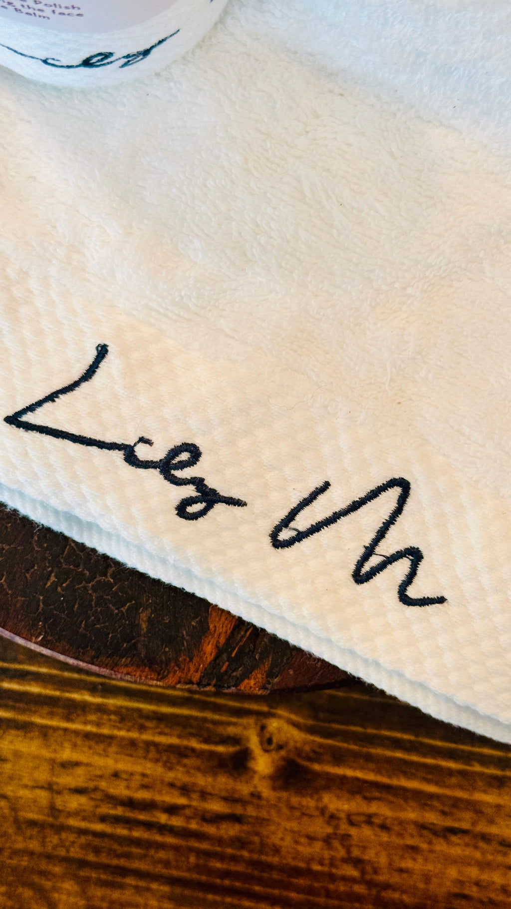 Close-up of the Lily M logo on the branded towel with dark green embroidery 