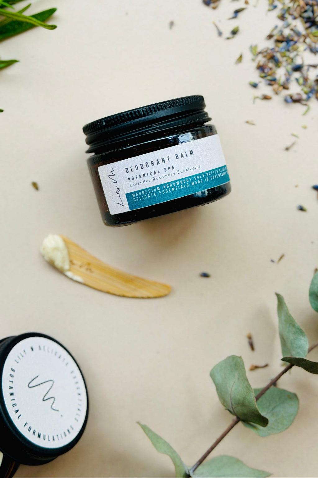 Jar of deodorant balm with botanicals on a light background