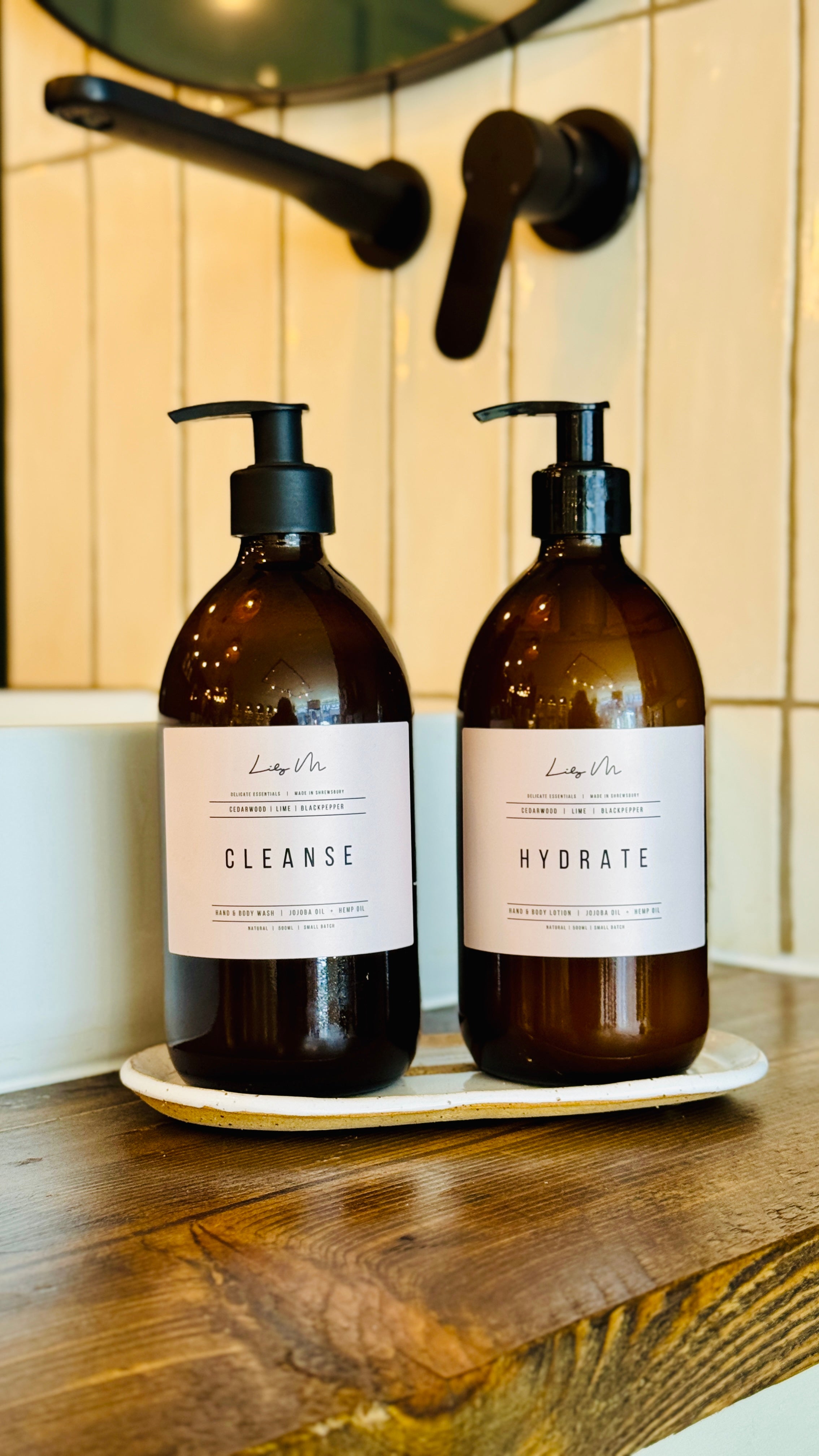 hand & body set, sat upon the handmade glazed white bottle tray by a sink 