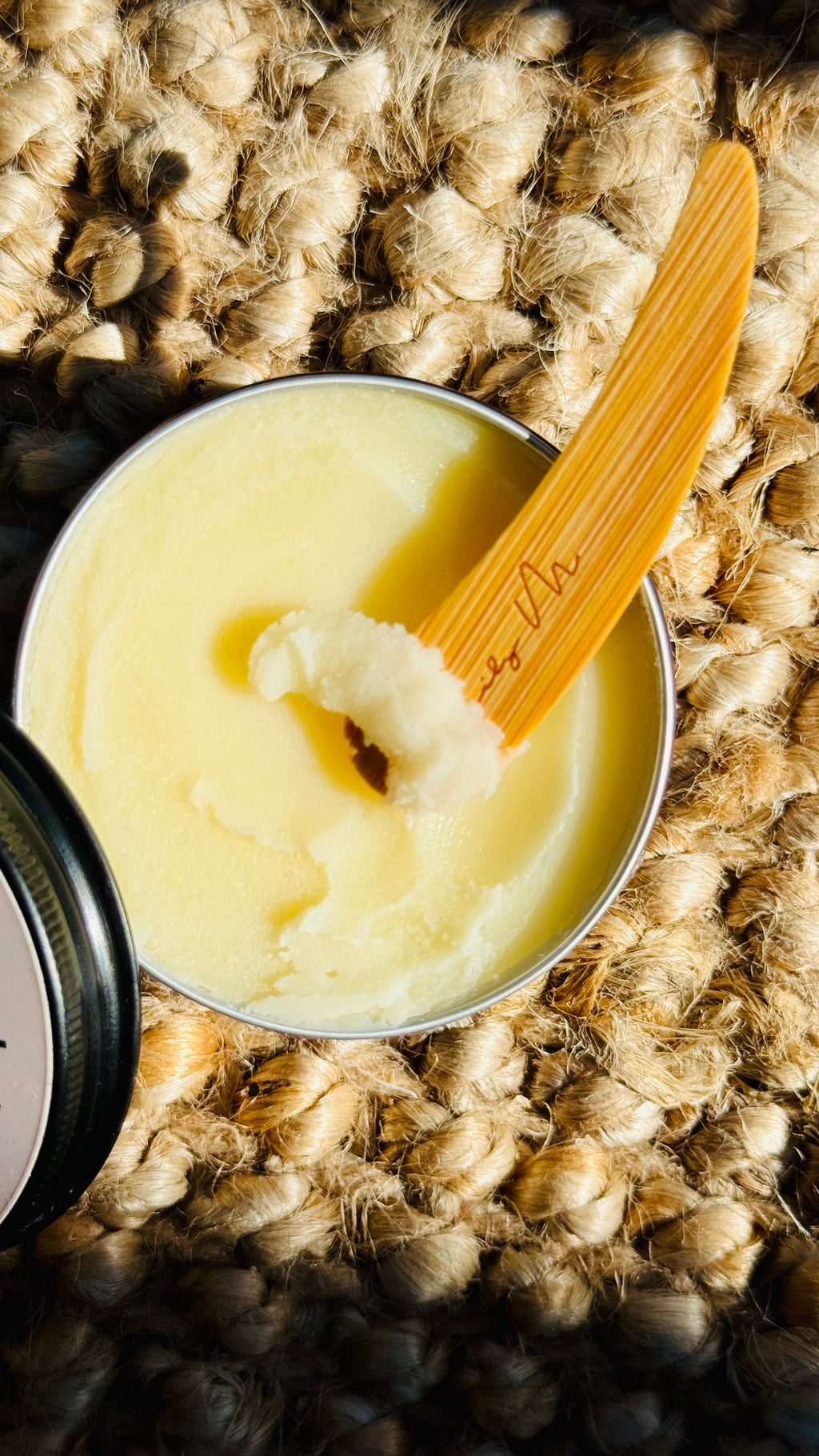 multi purpose balm with lid off and a wooden Lily M spatula, showing the texture