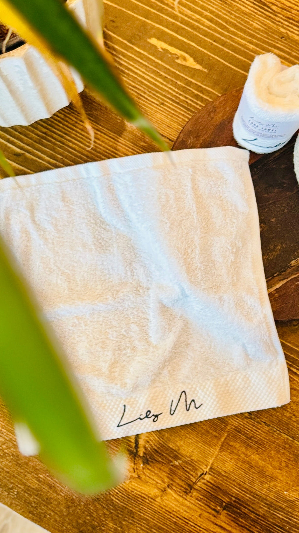 Lily M Branded face towel with an leaf in the foreground 