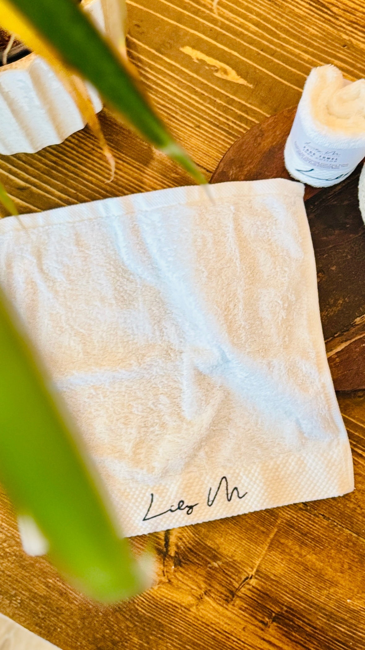 Lily M Branded face towel with an leaf in the foreground 