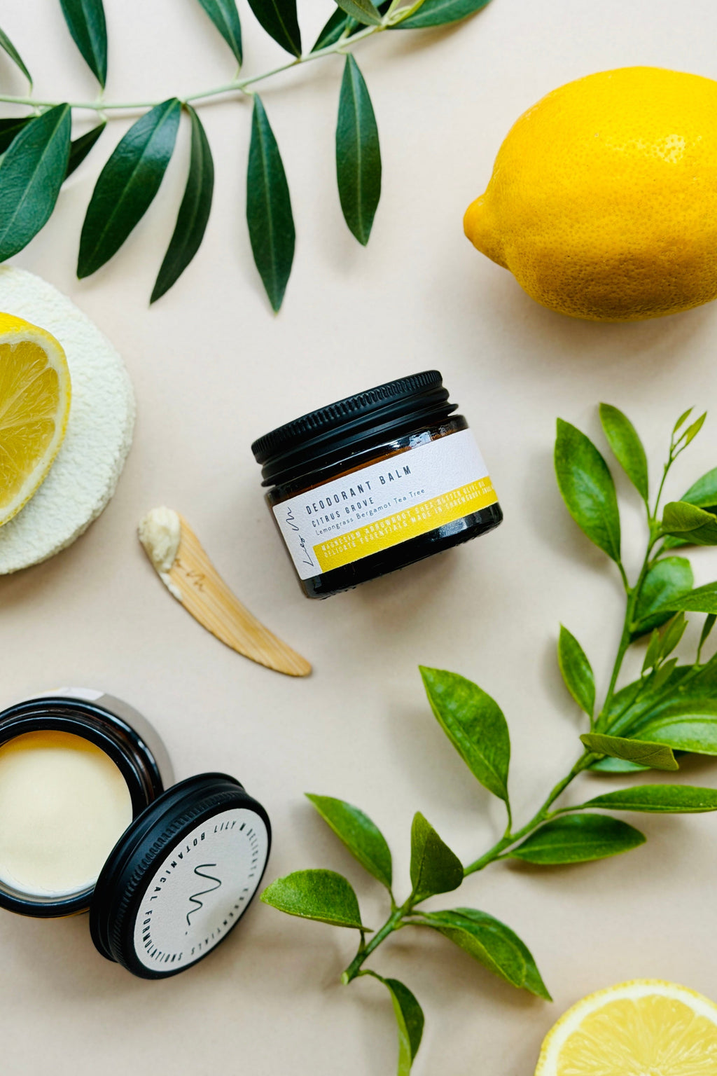Two jars of cream with a lemon and olive leaves on a light background