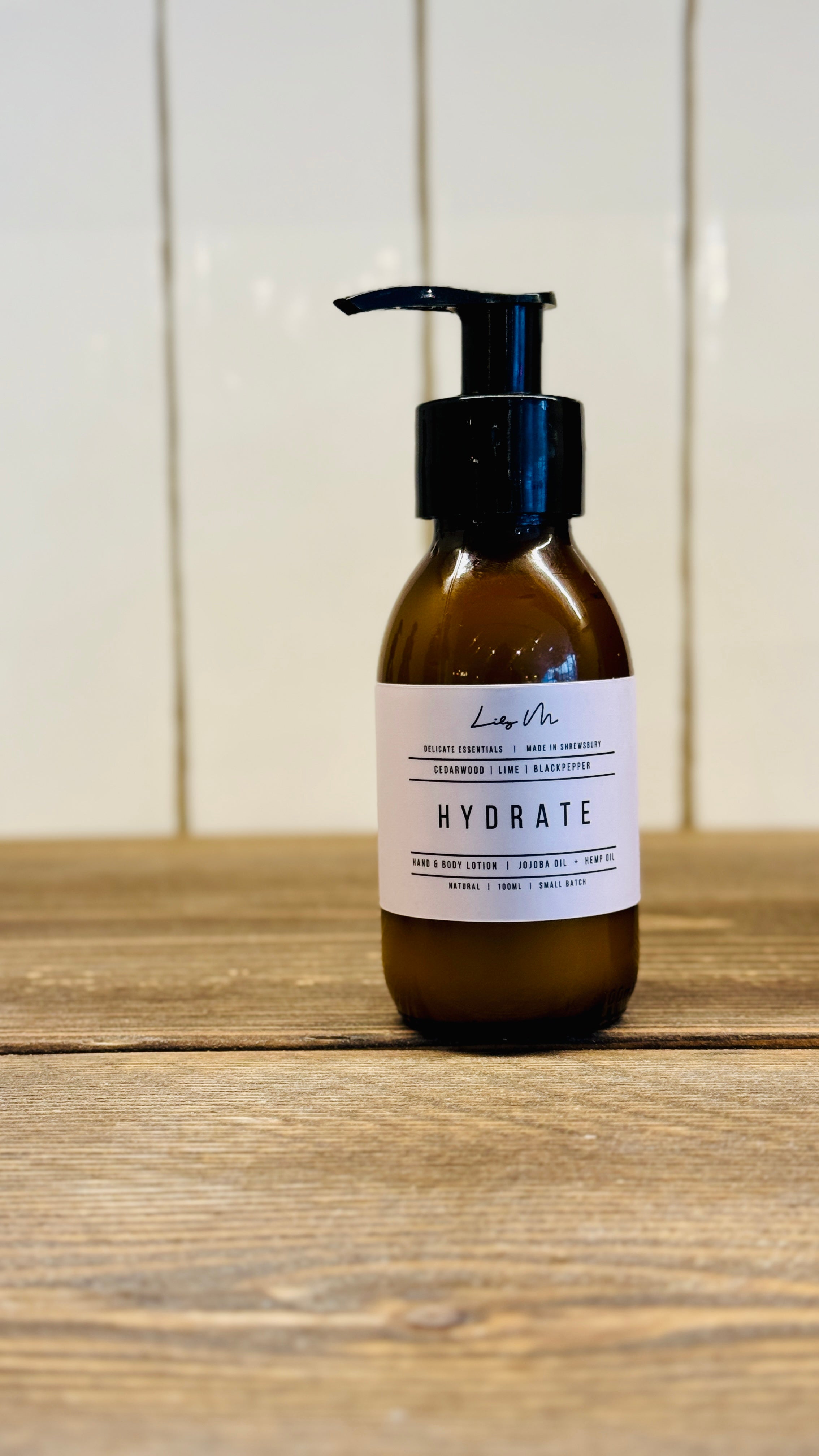 travel size 100ml hand and body lotion in a small amber glass bottle with a black pump