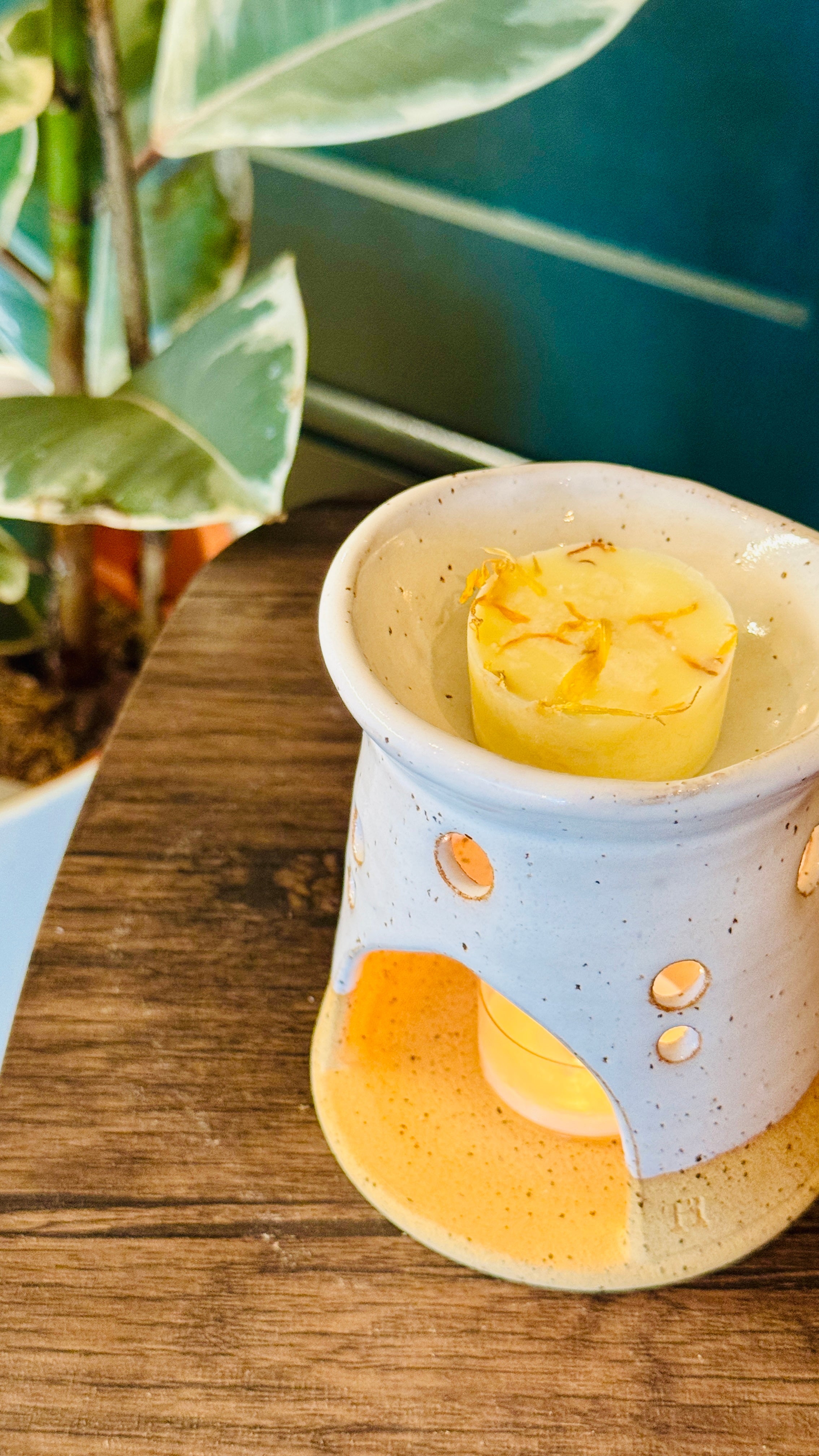 essential oil mandarin & Marjoram wax melt in the burner on a wooden table with the candle lit 